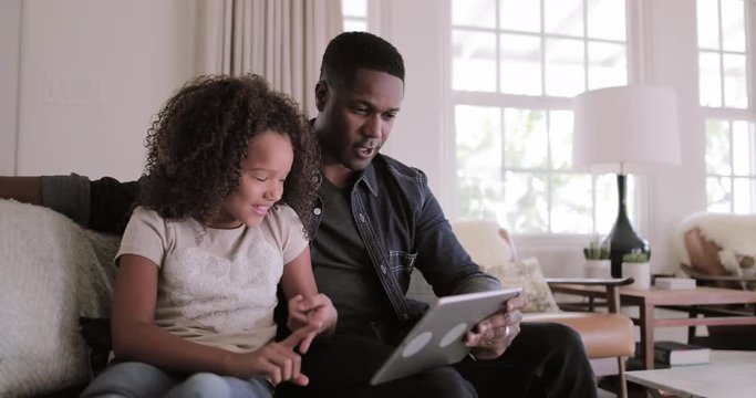 African American father and daughter using digital tablet together