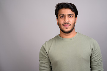 Portrait of young handsome Indian man against gray background - 237282917