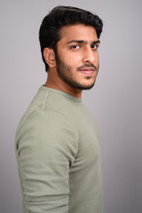 Portrait of young handsome Indian man against gray background