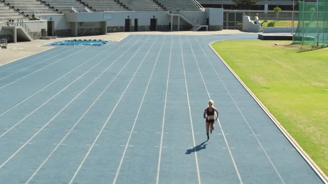 Fit woman running fast on racetrack during training session. Female runner approaching the finishing line on race track.
