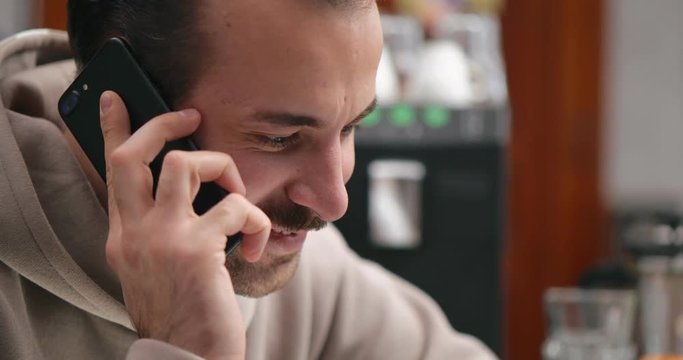Young attractive guy talking on the phone at the bar at hom