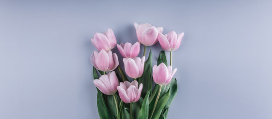 Bouquet of Pink tulips flowers over light blue background. Greeting card or wedding invitation. Flat lay, top view, copy space. Wide composition
