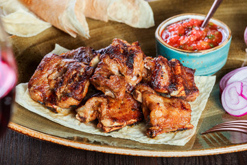 Roasted chicken with herbs, tomato sauce and glass of wine on a plate. Hot Meat Dishes