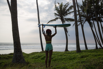Woman walking with her surfboard towards the ocean