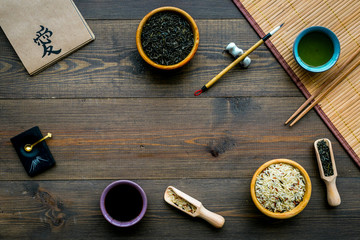 Chinese traditional symbols concept. Tea, rice, hieroglyph love, bamboo table mat, chopsticks, soy sause on dark wooden background top view frame space for text