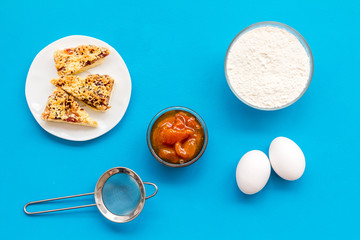 Cook cookies at home concept. Ingredients and instruments for make cookies. Fresh cookies near flour, eggs and sieve on blue background top view
