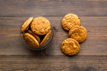 Homemade oatmeal cookies in glass bowl on dark wooden background top view