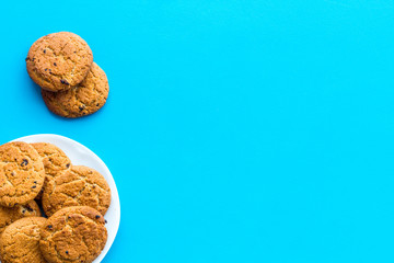 Fototapeta na wymiar Homemade oatmeal cookies on white plate on blue background top view space for text