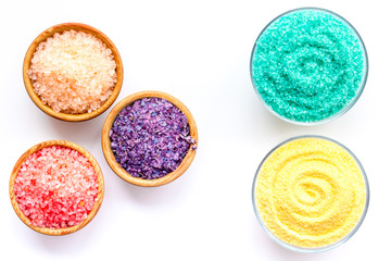 Spa salt background. Colorful spa salt in bowls on white background top view. Yellow, turquoise, pink, purple spa salt
