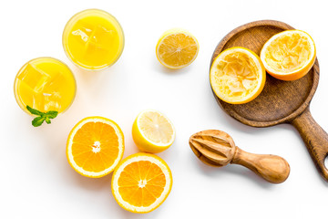 Squeeze fresh oranges with juicer. Orange juice in glass near half cut oranges on white background...
