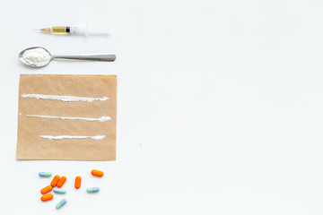Take drugs, drugs addiction concept. White powder like heroine or cocaine, drug tracks pills, spoon, syringe on white background top view copy space
