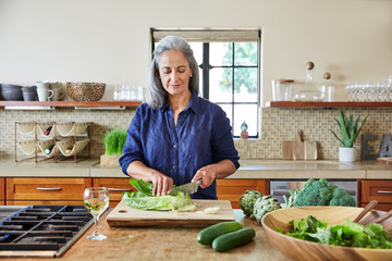 Mature woman preparing a healthy salad in the kitchen at home 