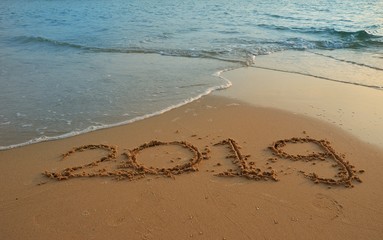 Happy new year concept, 2019 put on sand beach in sunrise.