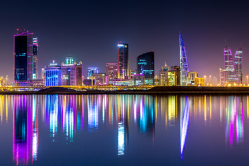 The skyline of Manama, capital of Bahrain with the World trade Center building at night and water...