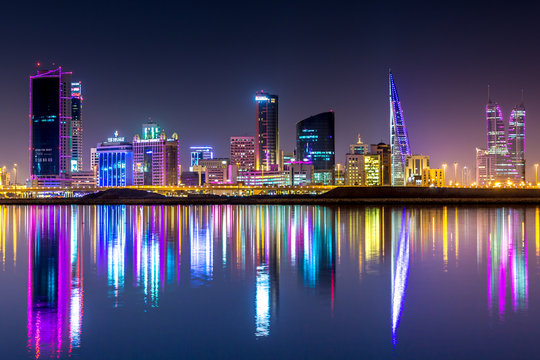 The skyline of Manama, capital of Bahrain with the World trade Center building at night and water reflection
