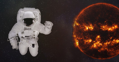 Astronaut in outer space near the Sun of solar system with reflection in helmet. Science fiction wallpaper. Elements of this image were furnished by NASA.