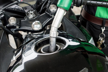 Close-up of someone refilling gas to the motorcycle barrel tank in gas petrol station.