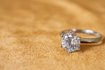 Jewelry diamond ring on golden fabric background close up