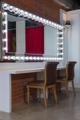 Beautiful interior of modern makeup room for beauty fashion with mirror lights illumination and white counter, wooden chairs vintage style decoration contemporary