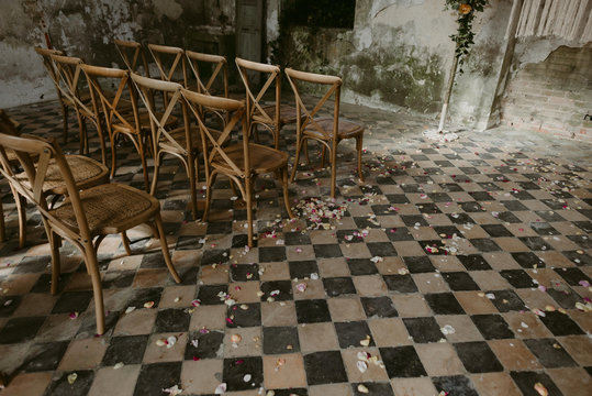 Wedding ceremony set up with wood chairs and flower petals on vintage 1900s checkered floor tile