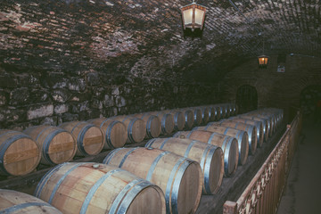 Wine barrels in a old cellar at winery. Wooden barrels of wine in vineyard.