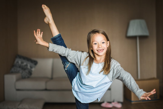 Cheeky little girl practicing gymnastics in her living room.