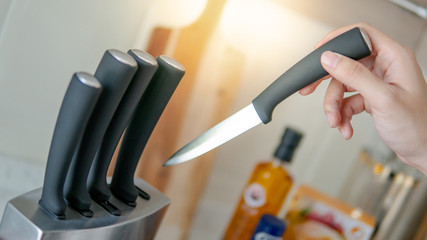 Male hand choosing knife from the set on vintage kitchen counter. Home living lifestyle in the...