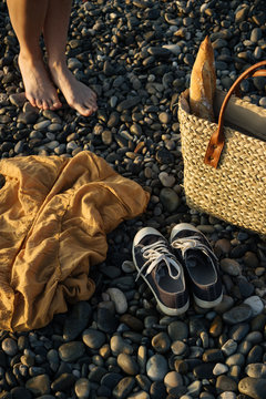 Unidentified person standing near shopping bag with baget, on a european rocky sea shore