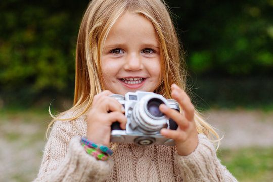 Portrait of a little girl holding an old camera.