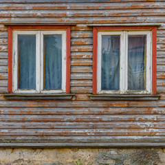 Fototapeta na wymiar Part of old building facade with two windows on wooden wall