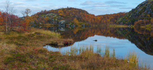 Autumn landscape. The rocks and the sky are reflected in the lake.