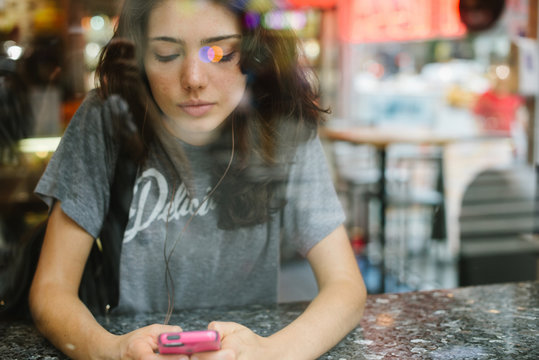 Young Woman Listening To Music In Bodega