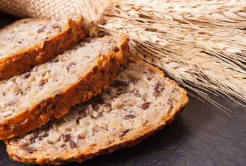 Slices of wholegrain bread for breakfast and ears of rye or wheat grain