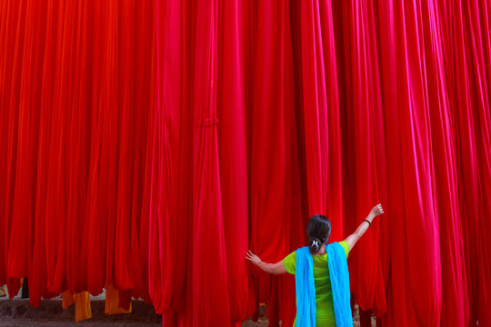 A woman holding the hanging colorful red clothes for drying purpose in a textile industry