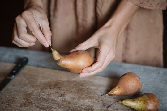 Anonymous woman cutting fresh pear