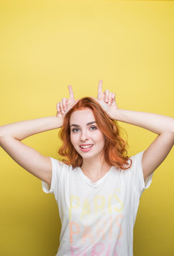 Studio Portrait Of Beautiful Redhead Girl Against The Yellow Background