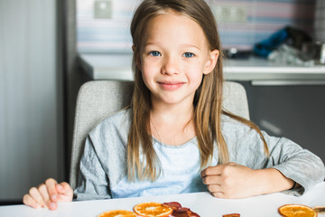 Cheeky cute blond little girl playing with dried fruit