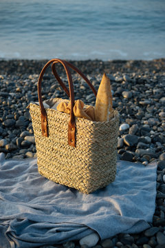 Grocery shopping bag with baget bread, standing on rocky sea shore