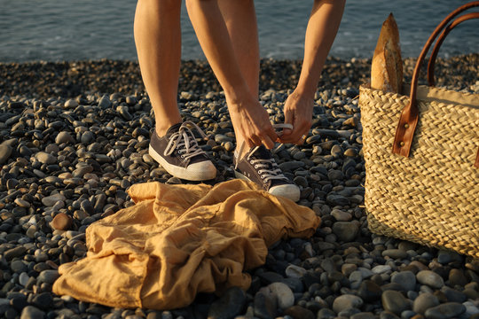 Unidentified person standing near shopping bag with baget, on a european rocky sea shore