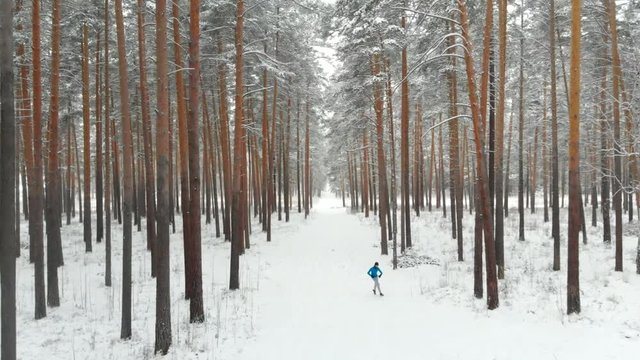 Winter Sports And Active Lifestyle Concept: Young Teen Man Running Outdoor Winter Forest Trail. Jogging In Winter. Male Runner in Park. Fitness and Wellness Concept. Healthy Lifestyle 