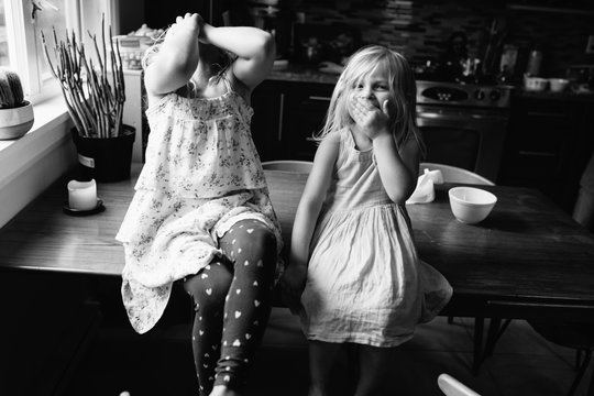 Two cute sisters sitting in kitchen together at home