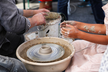 Hands of old man and young boy sculpt something by clay together