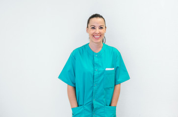 Happy young nurse in green uniform over a white wall