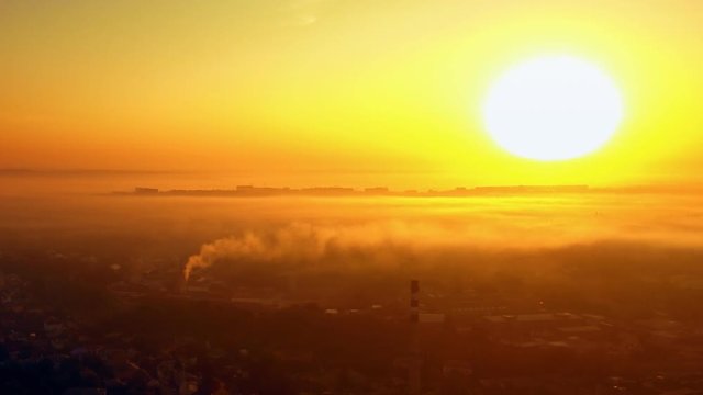 Aerial view of foggy sunrise over the city with building silhouettes on horizon. FullHD 1080p.