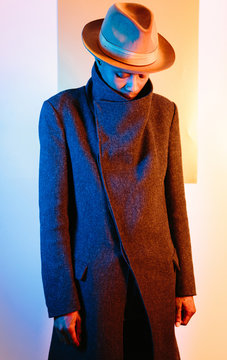 Portrait of man in hat and overcoat looking down