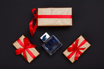 Gift boxes with ribbons and perfume on black background.