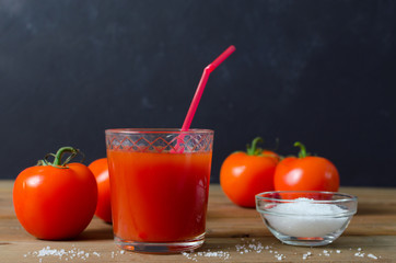 Tomato juice in glass with fresh tomatoes and salt. Rustic wooden background.