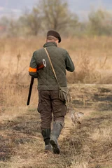Tuinposter The hunter in the hunting clothes and with rifle hunts © predrag1