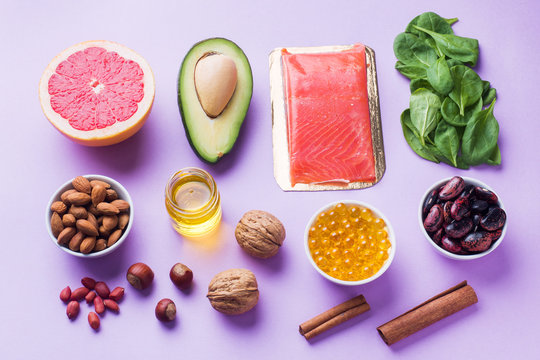 Concept Healthy food antioxidant products: fish and avocado, nuts and fish oil, grapefruit on pink background.