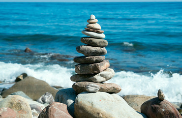 Pyramid of stones on the beach with bright sun. Crimea. Russia.